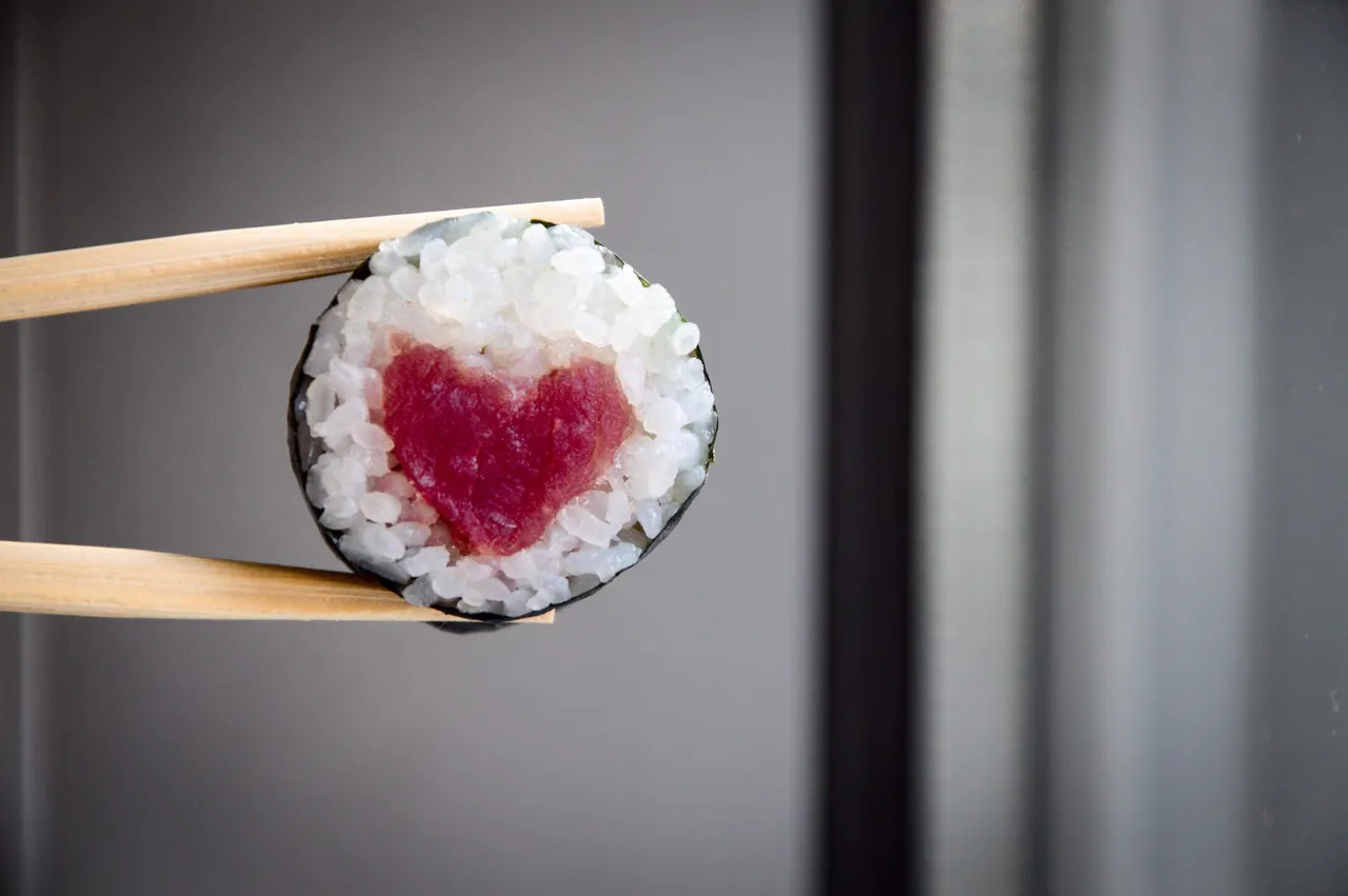 Rolka sushi z sercem z tuńczyka trzymana pałeczkami
