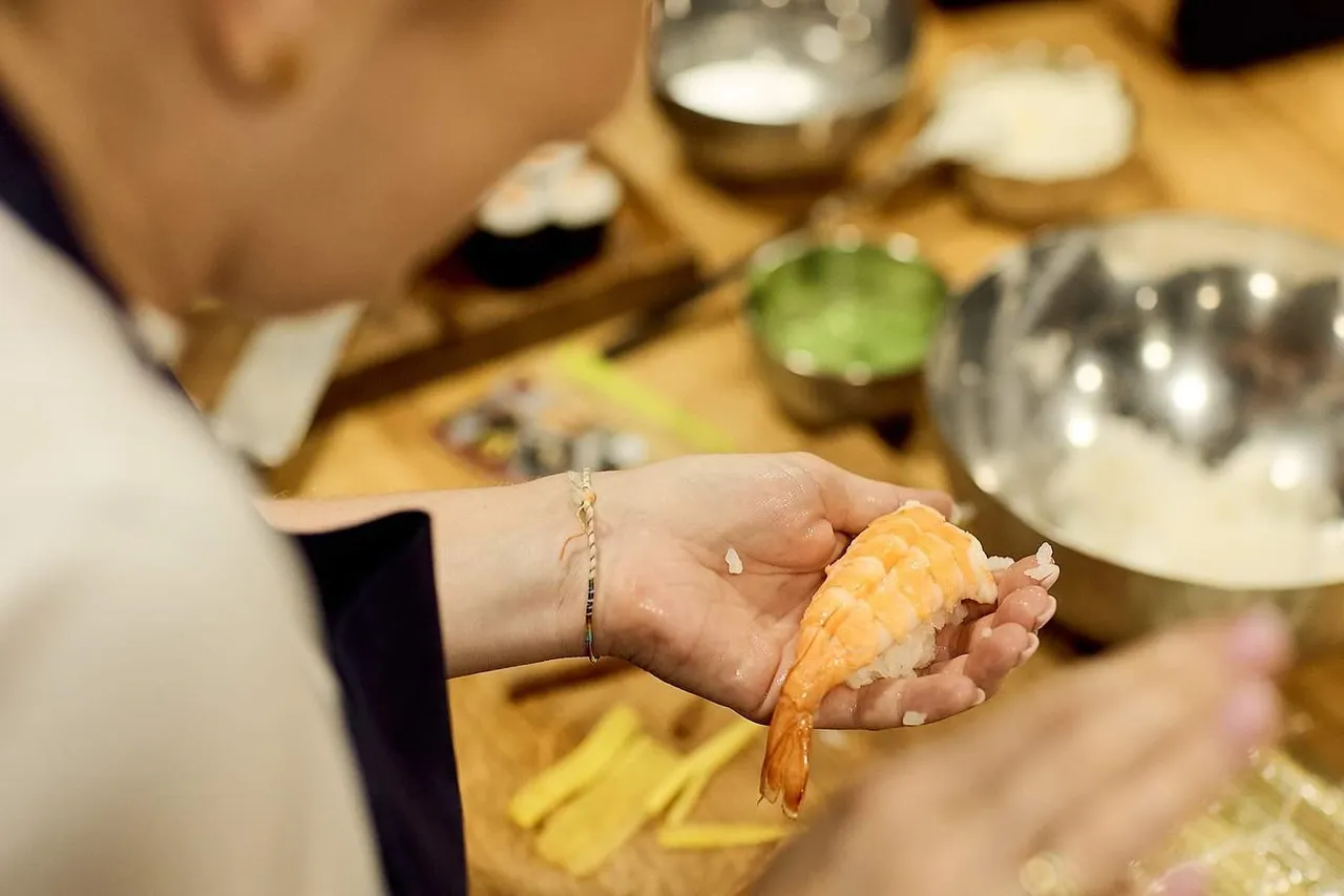Uczestniczka warsztatów formuje nigiri z krewetką